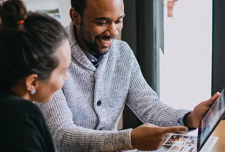 A Mac team member smiles while showing a client prospective properties on a tablet